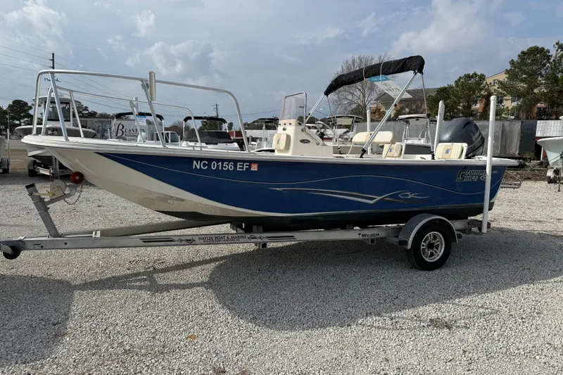 Slide: The Image of 2017 Carolina Skiff 218 DLV boat on trailer, blue and white design, parked outdoors. - 13