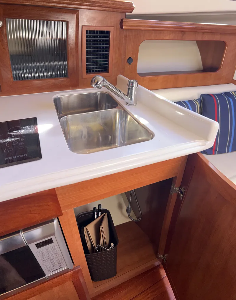 Slide: The Image of 2016 Marlow Pilot 31 kitchen with sink, wooden cabinetry, and striped cushion. - 27