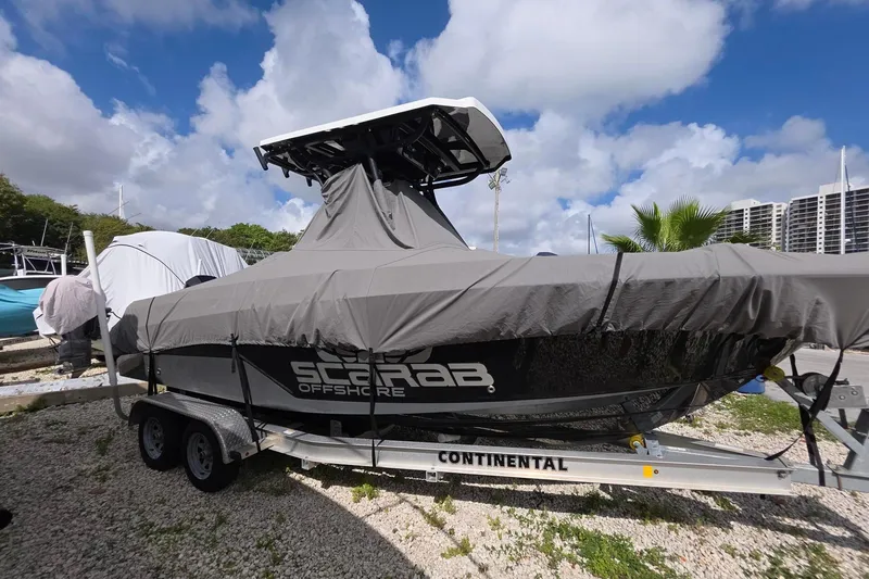 Slide: The Image of 2022 Wellcraft 222 Fisherman boat covered on trailer, parked outdoors under cloudy sky. - 3