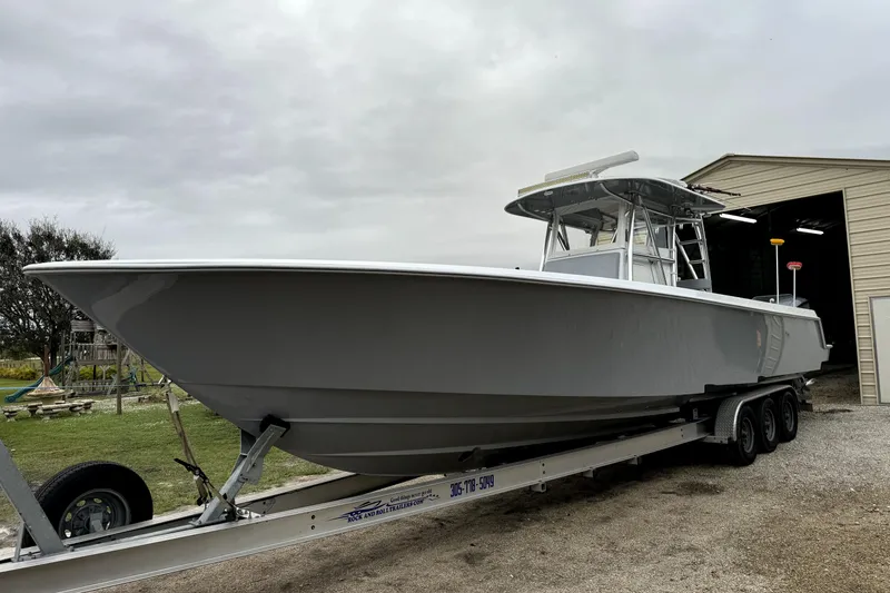 Slide: The Image of 2014 Contender 39 ST boat on trailer near a garage, overcast sky. - 12