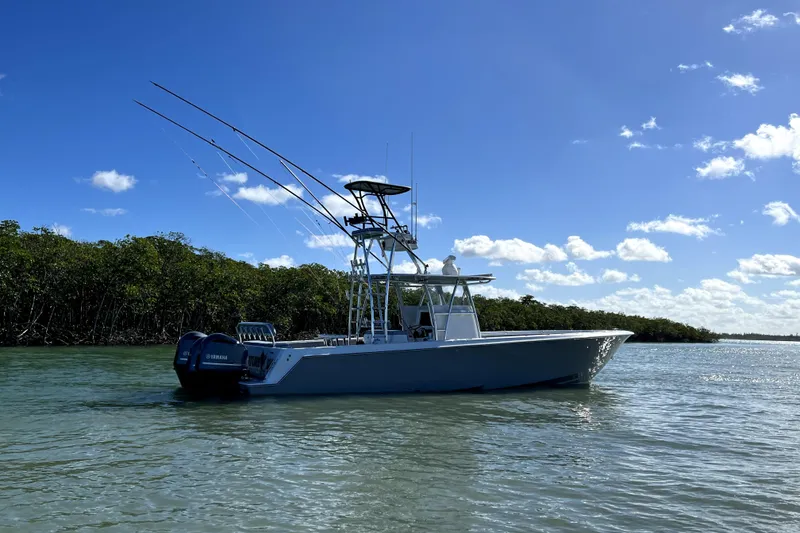 Slide: The Image of 2014 Contender 39 ST boat on calm water with clear blue sky and lush greenery. - 3