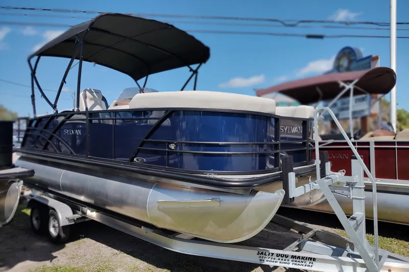 Slide: The Image of 2026 Sylvan MIRAGE X1 CLZ DH pontoon boat on trailer, featuring sleek design and canopy. - 7