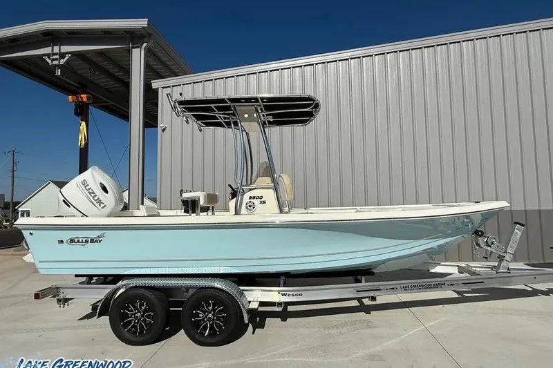 Slide: The Image of 2026 Bulls Bay 230 Center Console boat on trailer, parked outside metal building. - 1