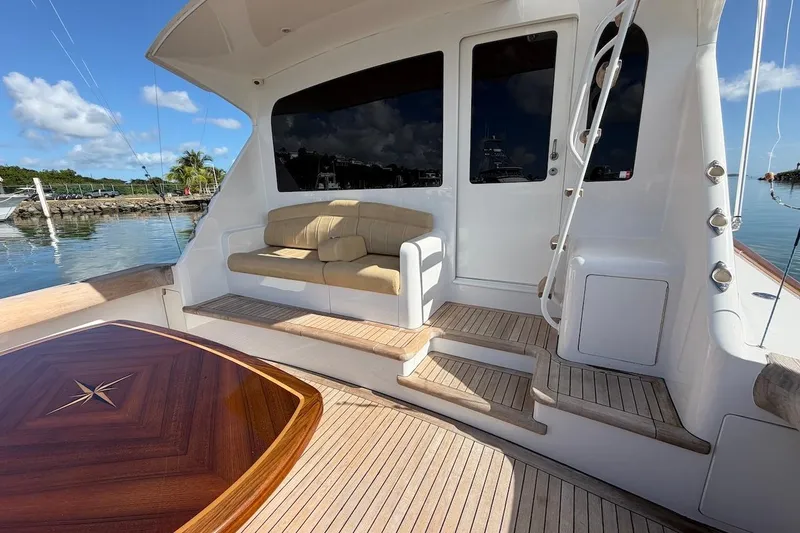 Slide: The Image of 2004 Viking 56 Convertible yacht deck with seating and wooden table, docked by the water. - 13