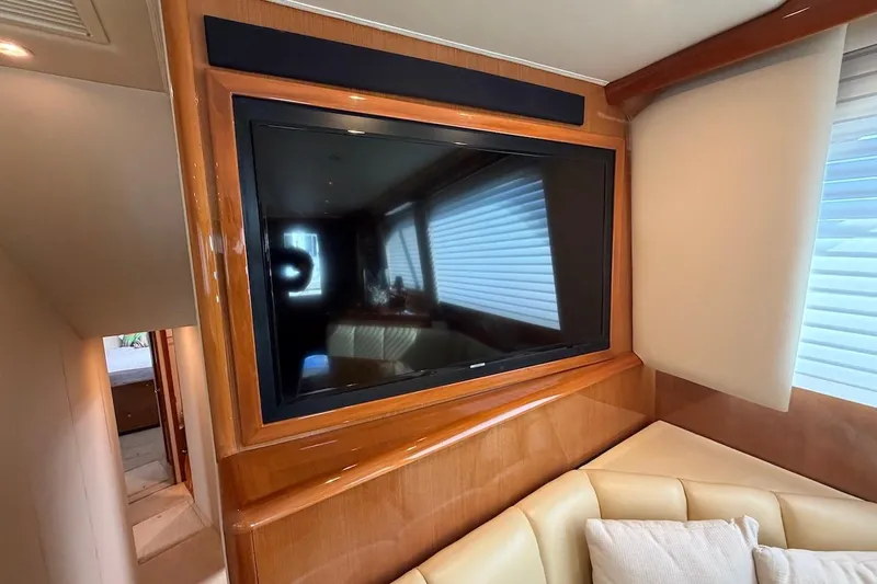 Slide: The Image of Interior of 2004 Viking 56 Convertible yacht with mounted TV and beige seating. - 23