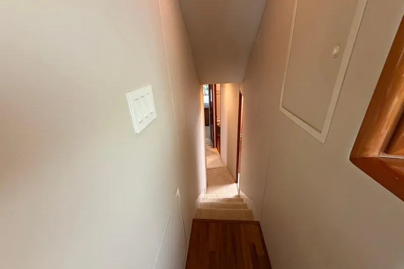 Slide: The Image of Narrow hallway inside 2004 Viking 56 Convertible yacht, featuring wooden accents and carpeted stairs. - 24