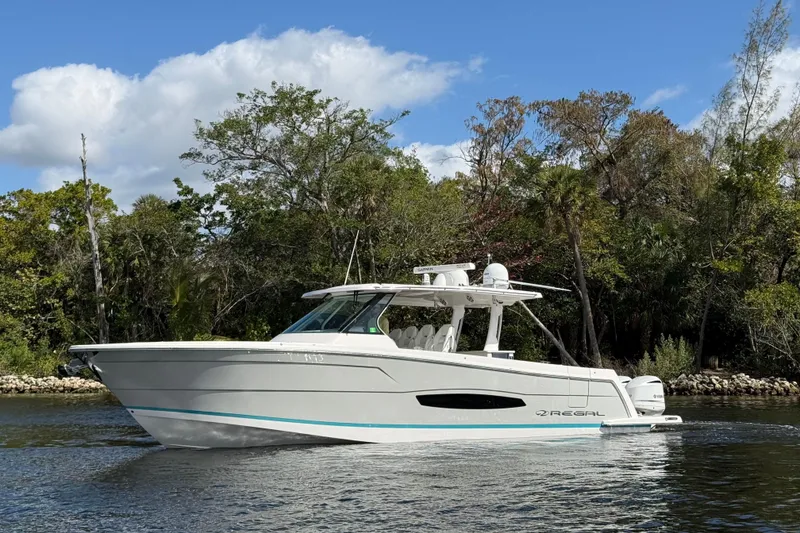 Slide: The Image of 2020 Regal 38 SAV boat cruising on a scenic river with lush greenery. - 10