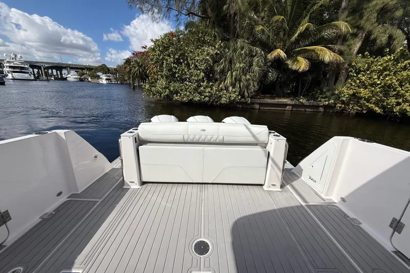 Slide: The Image of 2020 Regal 38 SAV boat deck with seating, surrounded by lush greenery and waterway. - 12