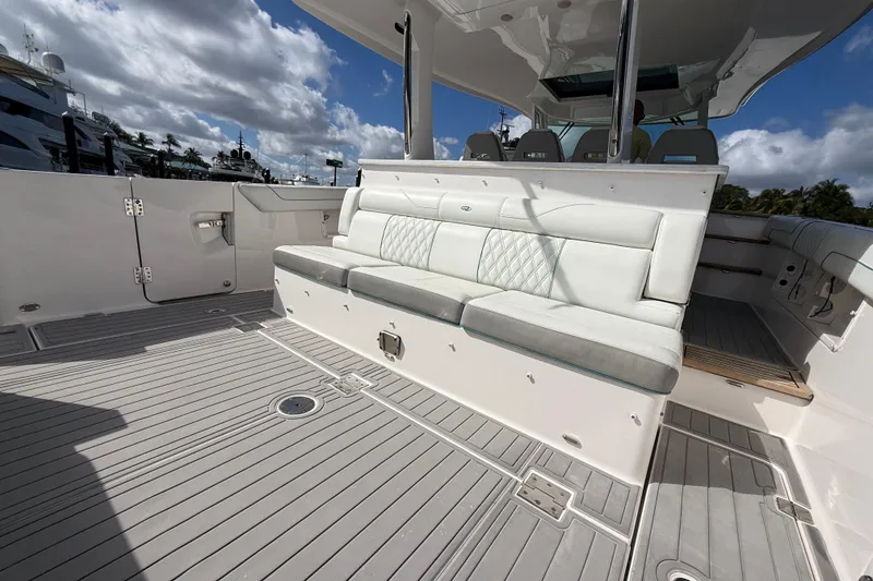 Slide: The Image of 2020 Regal 38 SAV boat deck with cushioned seating under a cloudy sky. - 14