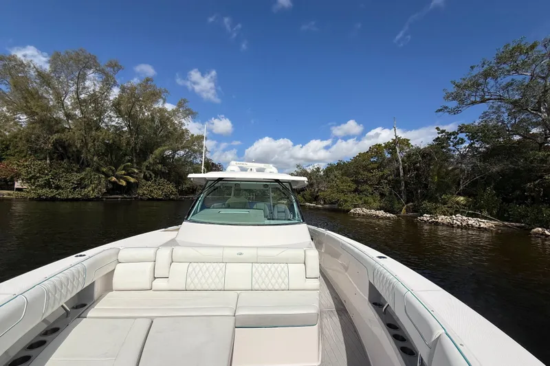 Slide: The Image of 2020 Regal 38 SAV boat cruising on a scenic river under a clear blue sky. - 27