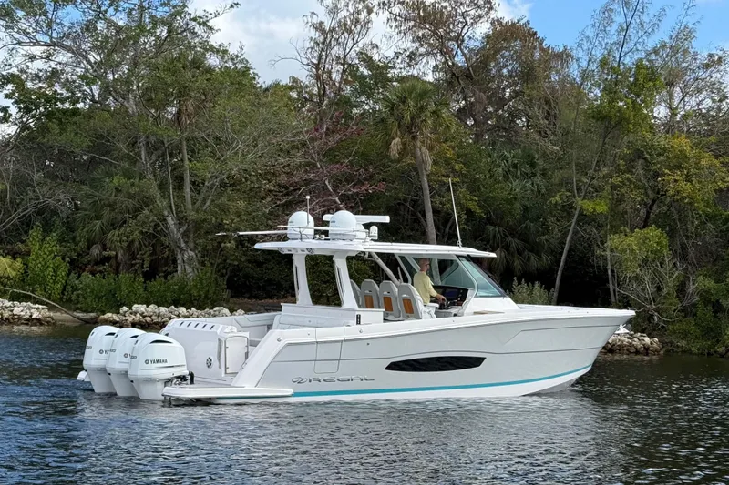 Slide: The Image of 2020 Regal 38 SAV boat cruising on a scenic waterway with lush greenery. - 3
