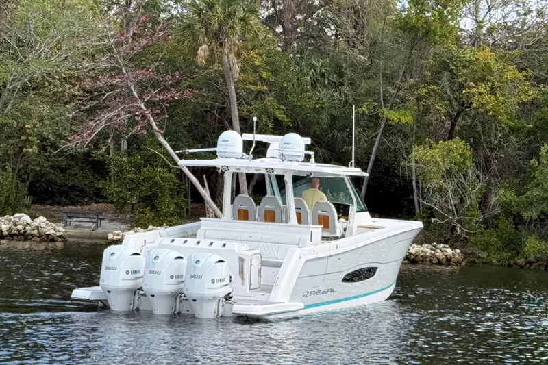 Slide: The Image of 2020 Regal 38 SAV boat cruising on a serene waterway surrounded by lush greenery. - 4