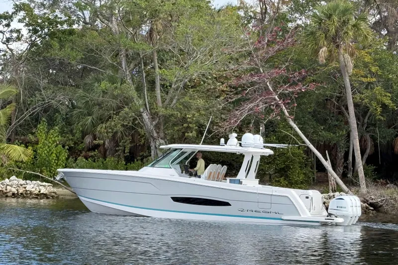 Slide: The Image of 2020 Regal 38 SAV boat cruising near lush, tropical shoreline. - 7