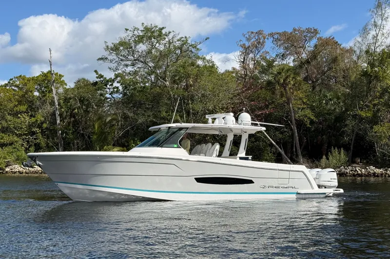 Slide: The Image of 2020 Regal 38 SAV boat cruising on a calm river with lush greenery background. - 9