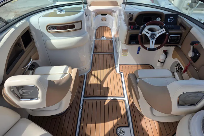 Slide: The Image of 2017 Crownline Eclipse E6 XS boat interior with tan and white seating, wood flooring, and steering console. - 9