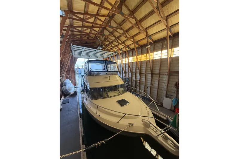 The Image of 1994 Carver 320 Voyager boat docked in a wooden boathouse. - 1