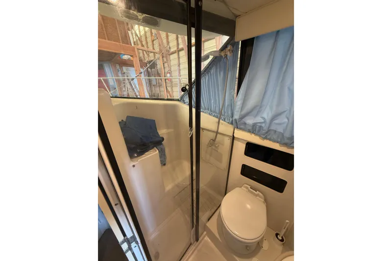 Slide: The Image of 1994 Carver 320 Voyager bathroom with shower, toilet, and blue curtains. - 14