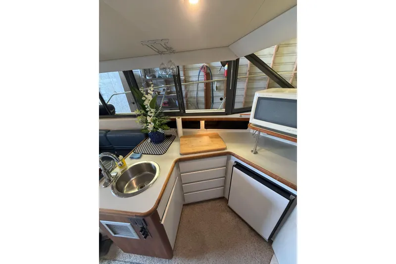 Slide: The Image of 1994 Carver 320 Voyager yacht kitchen with sink, microwave, and floral arrangement. - 18