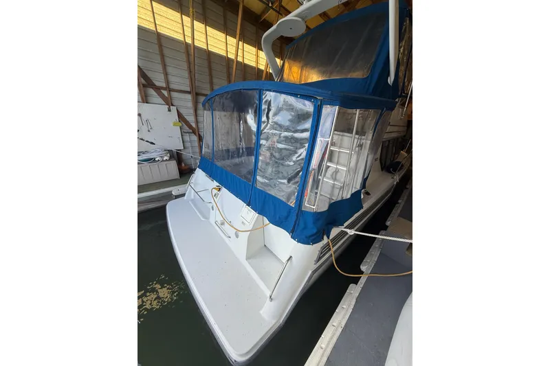Slide: The Image of 1994 Carver 320 Voyager boat with blue canopy docked indoors. - 4