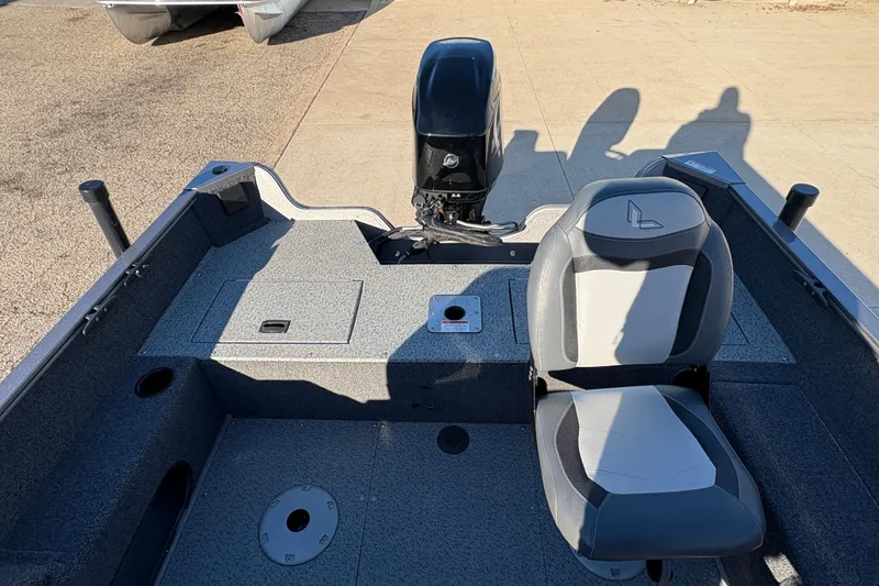 Slide: The Image of 2023 Lowe Fishing Machine 1675SC interior with seating and motor, docked on concrete. - 18