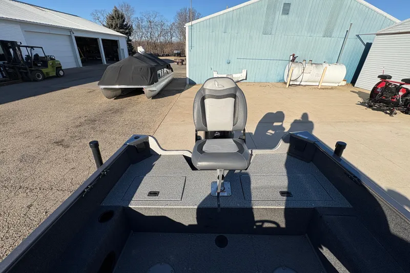 Slide: The Image of 2023 Lowe Fishing Machine 1675SC boat with seating, parked outdoors near buildings. - 22