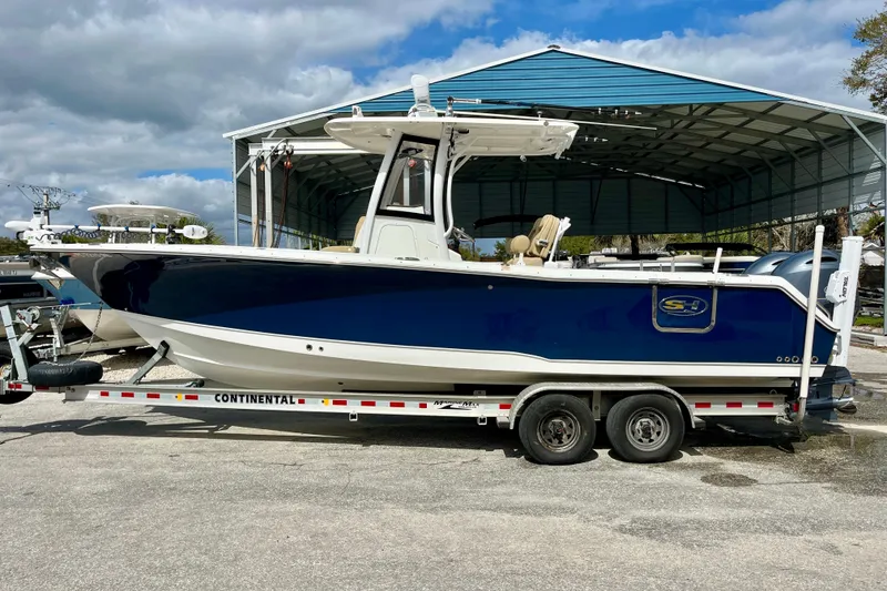 Slide: The Image of 2018 Sea Hunt Gamefish 27 Coffin Box boat on trailer under a metal canopy. - 1