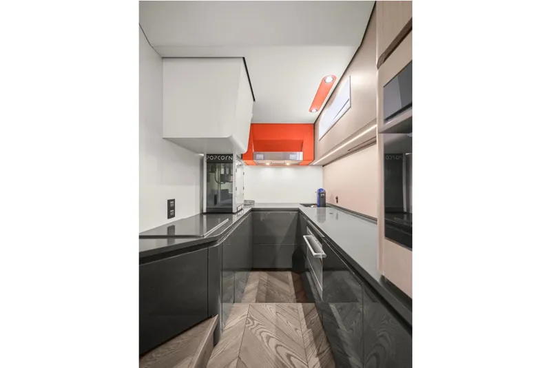 Slide: The Image of Modern kitchen interior with sleek black countertops, red accents, and wood flooring in a 2025 Maori 64 model. - 24