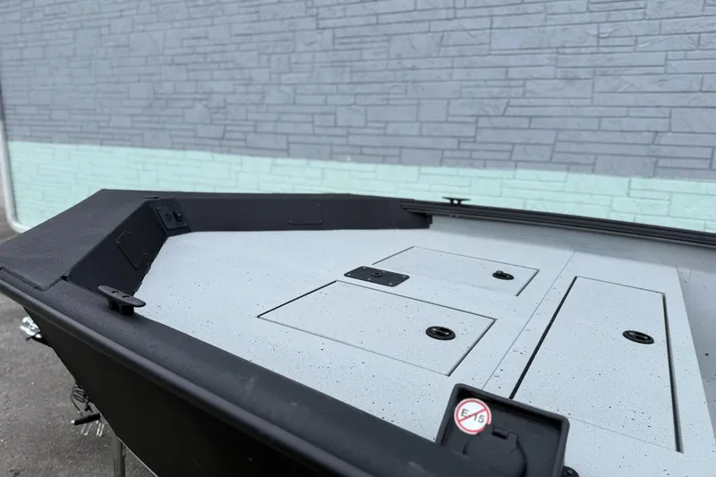 Slide: The Image of 2026 SeaArk Shadow 20 boat interior with storage compartments, against a textured wall background. - 13