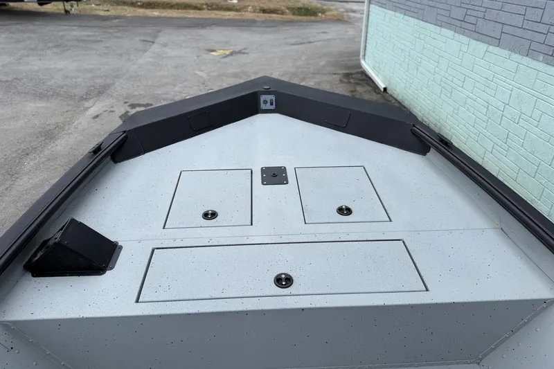 Slide: The Image of 2026 SeaArk Shadow 20 boat deck with storage compartments, parked near a brick wall. - 7