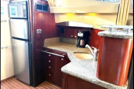 Slide: The Image of 2005 Sea Ray 420 Sedan Bridge kitchen with modern appliances and wood cabinetry. - 16