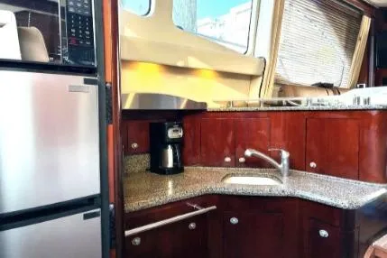 Slide: The Image of 2005 Sea Ray 420 Sedan Bridge kitchen with granite countertops, stainless steel appliances, and wood cabinetry. - 17