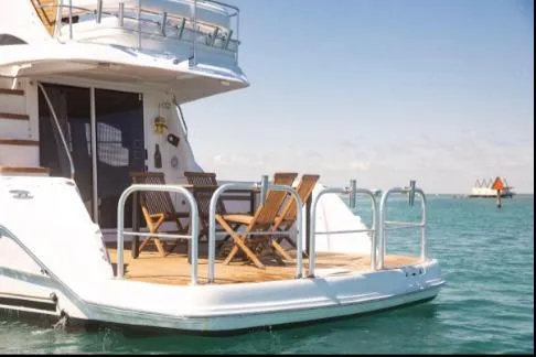 Slide: The Image of 2005 Sea Ray 420 Sedan Bridge yacht with deck chairs on calm water. - 2