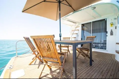 Slide: The Image of 2005 Sea Ray 420 Sedan Bridge yacht deck with wooden chairs and table under umbrella. - 6