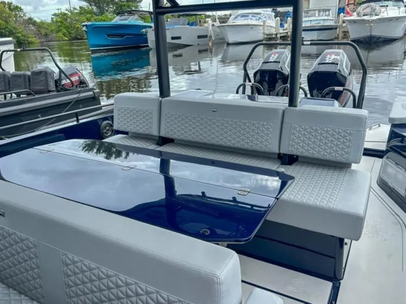 Slide: The Image of 2024 BRABUS Shadow 1000 ST luxury boat interior with seating and table, docked at marina. - 24