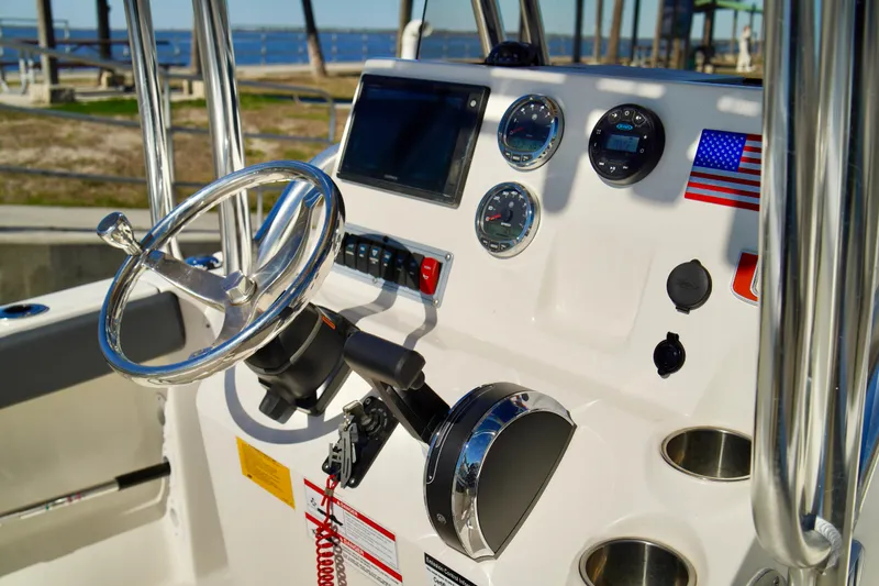 Slide: The Image of 2020 Key West 203 FS boat dashboard with steering wheel and gauges, featuring American flag decal. - 13