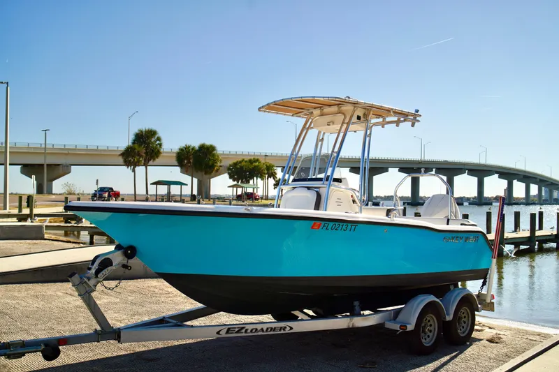 Slide: The Image of 2020 Key West 203 FS boat on trailer by waterfront, under clear blue sky. - 2