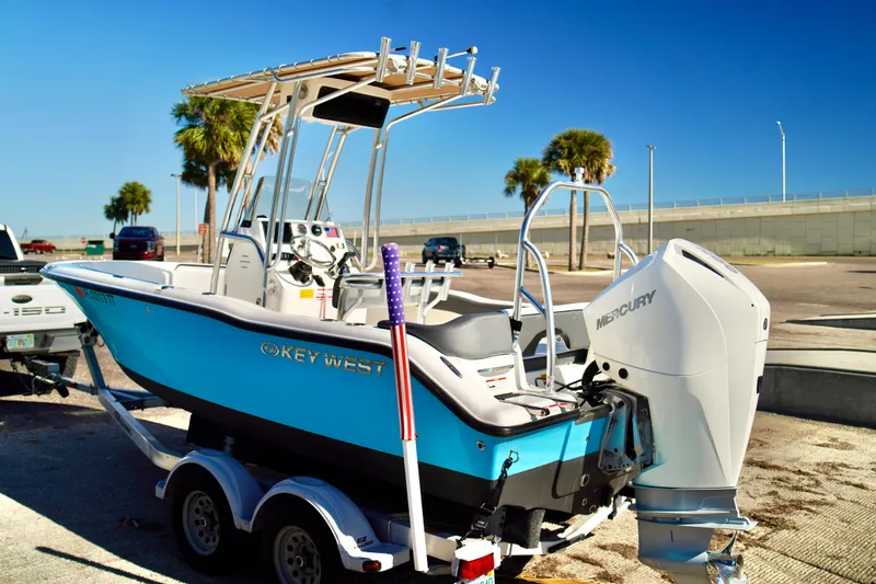 Slide: The Image of 2020 Key West 203 FS boat on trailer with Mercury engine, parked near palm trees. - 24