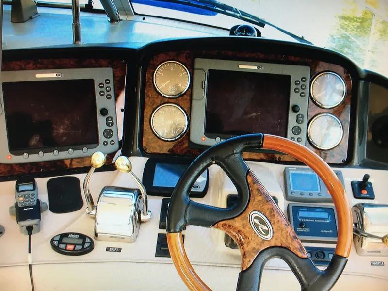 Slide: The Image of 2005 Sea Ray 500 Sundancer helm with wood-accented steering wheel and dual navigation screens. - 22