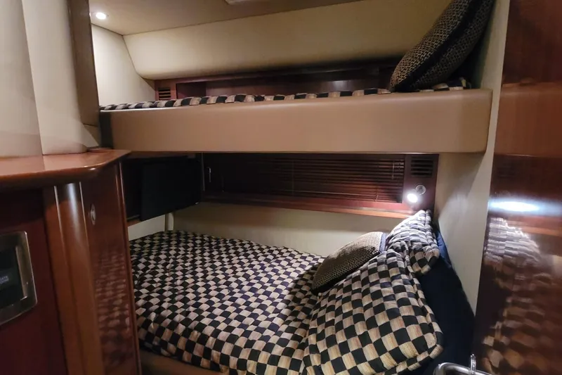 Slide: The Image of 2005 Sea Ray 500 Sundancer cabin with cozy bunk beds and checkered bedding. - 48