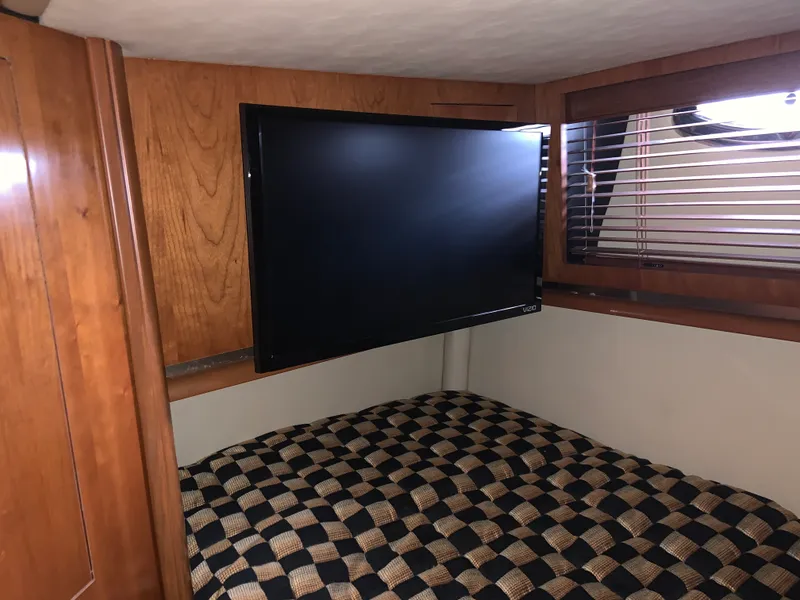 Slide: The Image of 2005 Sea Ray 500 Sundancer cabin with TV and checkered bedding. - 49