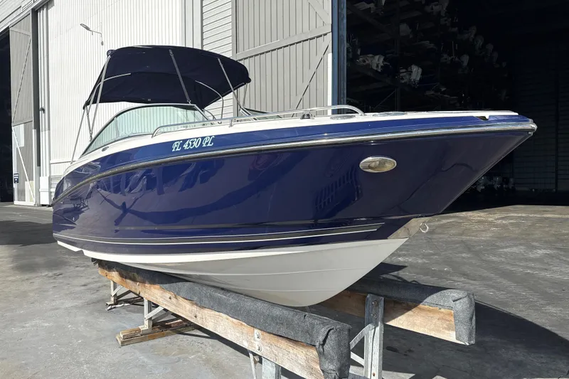 Slide: The Image of 2013 Monterey 264FS boat in storage, featuring a sleek blue and white design. - 0