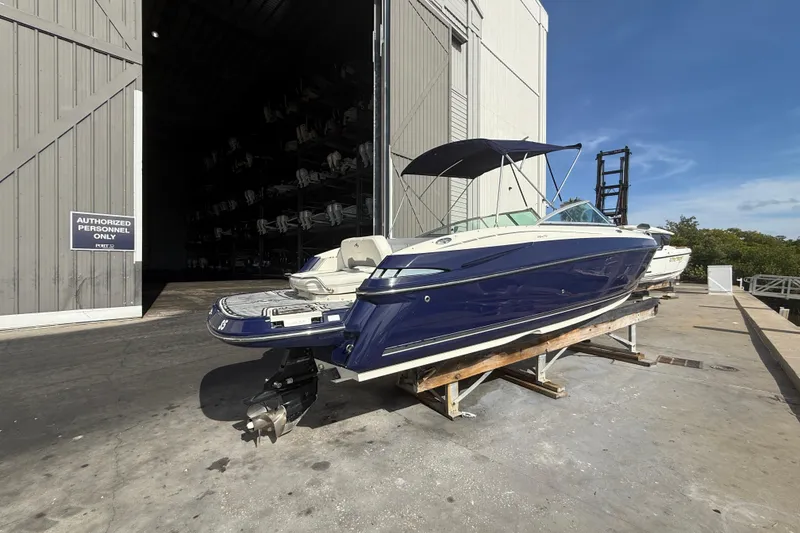 Slide: The Image of 2013 Monterey 264FS boat on dock, blue hull, near storage facility. - 1