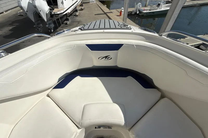 Slide: The Image of 2013 Monterey 264FS boat interior with white and blue seating at a marina. - 10