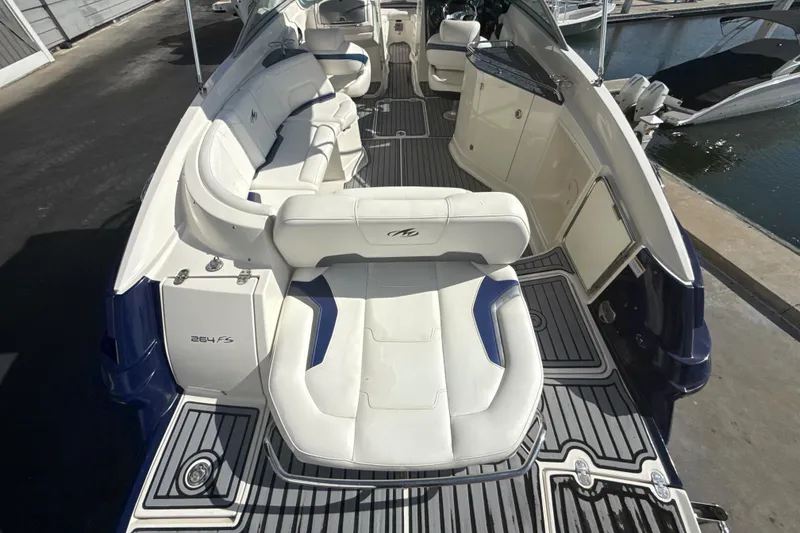 Slide: The Image of 2013 Monterey 264FS boat interior with white seating and sleek design at a marina. - 19