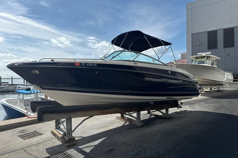 Slide: The Image of 2013 Monterey 264FS boat on a dock, with a blue canopy, under a clear sky. - 2