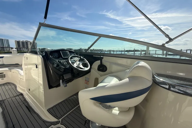 Slide: The Image of 2013 Monterey 264FS boat cockpit with steering wheel, dashboard, and seating under clear blue sky. - 7