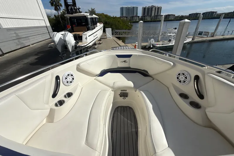 Slide: The Image of 2013 Monterey 264FS boat interior with white seating and cup holders at a marina. - 9