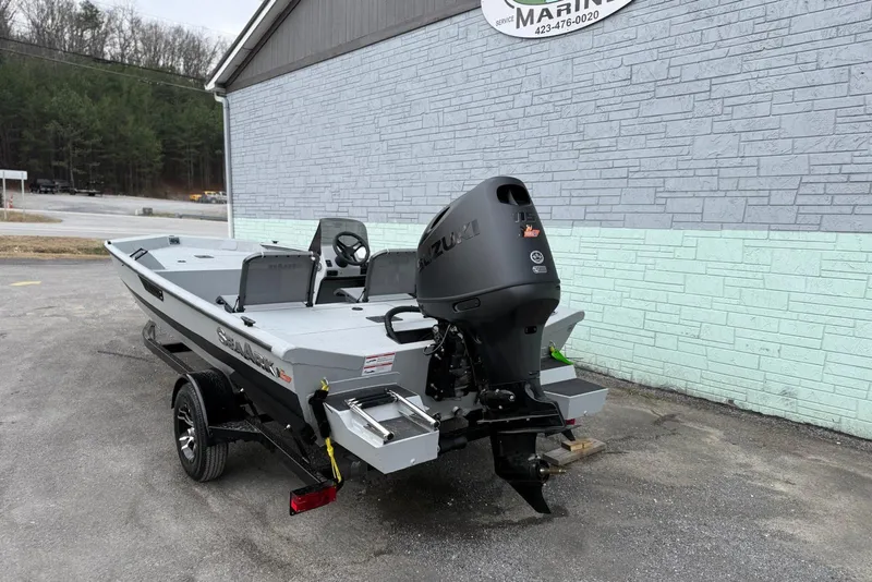 Slide: The Image of 2026 SeaArk Shadow 187 boat with Suzuki outboard motor, parked outside a marina. - 6