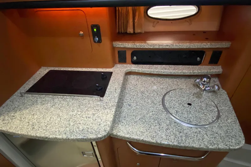 Slide: The Image of 2005 Chaparral Signature 310 boat kitchen with granite countertop and stove. - 11