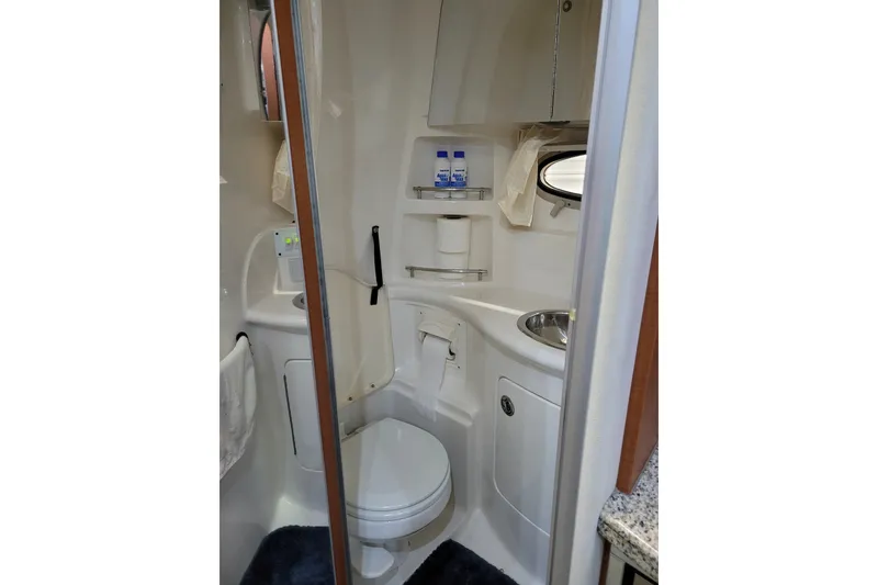 Slide: The Image of 2005 Chaparral Signature 310 boat bathroom with toilet, sink, and storage shelves. - 13